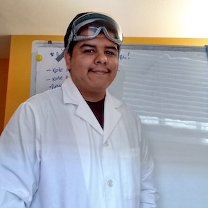Joseph Cruz in white lab coat with safety goggles